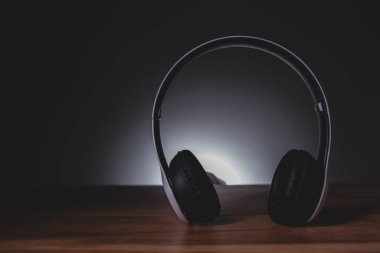 Siyah arka planda ahşap bir masa olan kulaklıklar.
