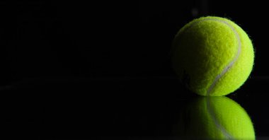 siyah arka plan üzerinde topu ve tenis raketi