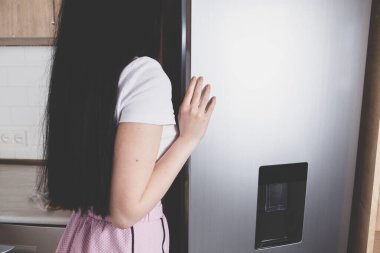 Genç bayan mutfağın yanında duruyor.