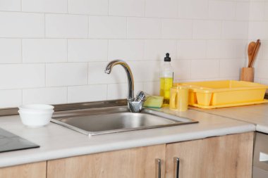 Modern mutfağın içinde beyaz lavabo ve ahşap çatal bıçak var.