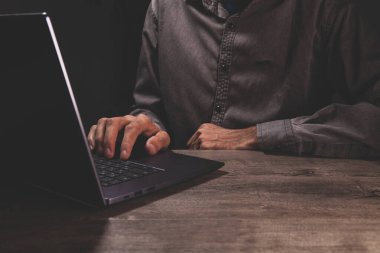 Beyaz gömlekli bir adam siyah bir bilgisayar klavyesinde daktilo ediyor.