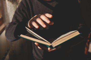Genç adam bir kafede kitap okuyor.