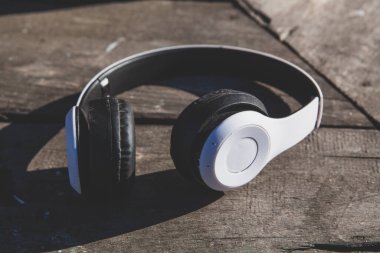 white headphones with white leather on black wooden background.