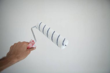 Beyaz duvar arkaplanını temizlemek için beyaz pamuklu çubuk tutuyordu..