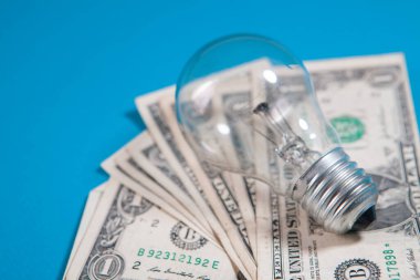 Ahşap bir arka planda ampulle para biriktirmek