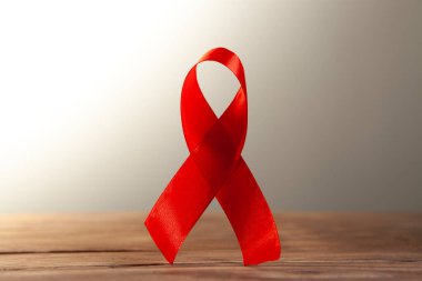 Gri arkaplandaki tahta masada kırmızı kurdele. Dünya AIDS Günü konsepti