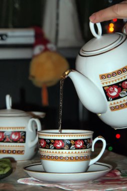 Bir kadın yaklaşan Yılan Yılı boyunca çaydanlıktan bardağa çay döker. Arka planda boa yılanı görebilirsiniz. Yakın plan..