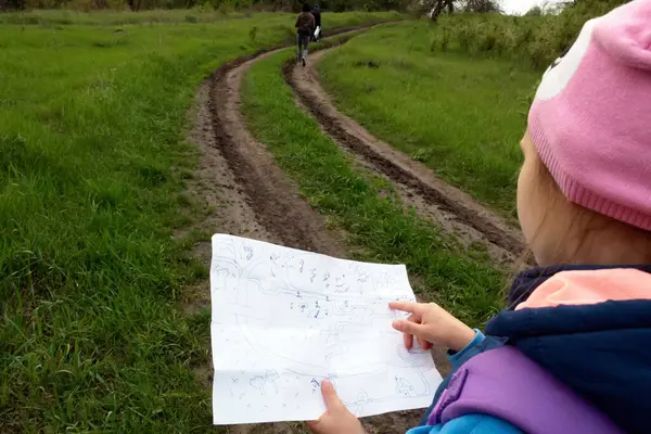Aile turizmi. Kayıp bir göle doğru yürüyüş. Genç bir kız hareket güzergahının haritasını çıkarıyor..