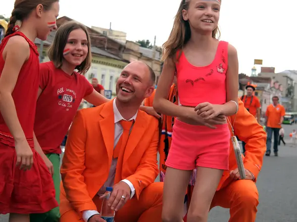 Kharkiv, Ukrayna - Haziran 09.2012: Euro 2012 döneminde turuncu giysili Hollandalı taraftarlar, yüzlerinde Hollanda bayrakları olan ve bir dakika önce yanlarında fotoğraflanan çocuklar tarafından çevrelendiler..