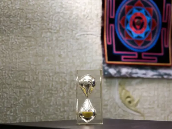 Kum saati düz, karanlık bir yüzeyde. Arkanızdaki duvara bir çeşit yantra bağlanmış. Genel olarak, aktif ilke ve sürekli yaratılış sürecini sembolize eder. Yazıtın sol tarafta olabilir..