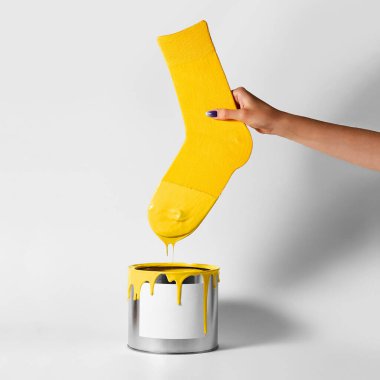 Dişi bir el sarı çorabını boya kutusuna daldırıyor.