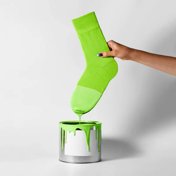 stock image A female hand dips her green sock into a can of paint