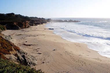 Pasifik Okyanusu kıyısında kayalıklar, kayalar, kum ve dalgalarla