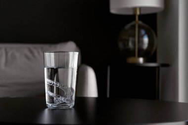 Şeffaf görünmez ortodontik diş hizalayıcılar, dairedeki bir masada suyla bardakları temizleyen diş koruyucular.