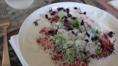 Parmesan peyniri ile süslenmiş çiğ et yemeği ve iştah açıcı bir restoranda yapraklar.