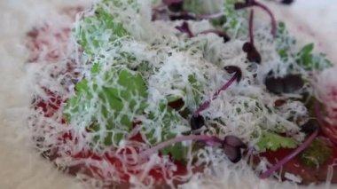 Parmesan peyniri ile süslenmiş çiğ et yemeği ve iştah açıcı bir restoranda yapraklar.
