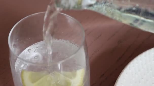 炭酸レモン水泡状の炭酸飲料ガラスの前景ガラス瓶に注ぐ — ストック動画