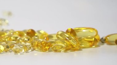 Beyaz arka planda saydam altın hapların yakın plan görüntüsü. Petrol Hapları Kapsülü Cilt Bakımı Tıbbi Avrupa 4k