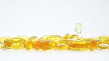 Beyaz arka plana düşen saydam altın haplar. Petrol hapları kapsül Cilt bakımı Tıbbi Avrupa 4k