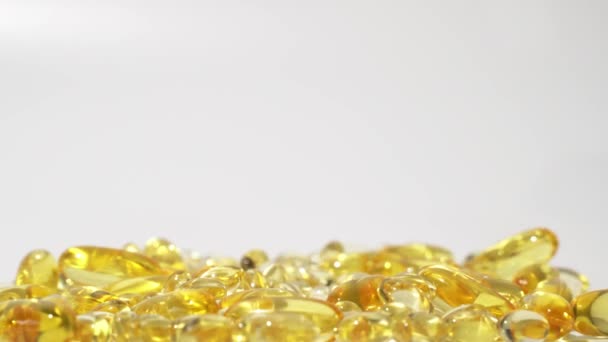 透明な金色の錠剤が白い背景に落ちています オイルカプセルスキンケア医療ヨーロッパ4K — ストック動画