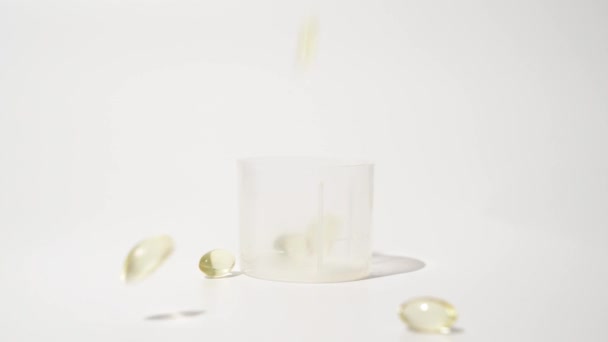 Průhledné Zlaté Pilulky Padající Bílé Pozadí Olejové Pilulky Kapsle Péče — Stock video