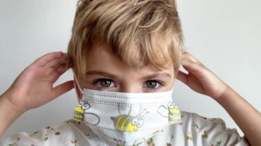 Yüzüne beyaz bir maske takan gülümseyen çocuk yüzünü kapat. Grip koruması için çocukların güvenliği, vesikalık portreyi kapatın. Boşluğu kopyala