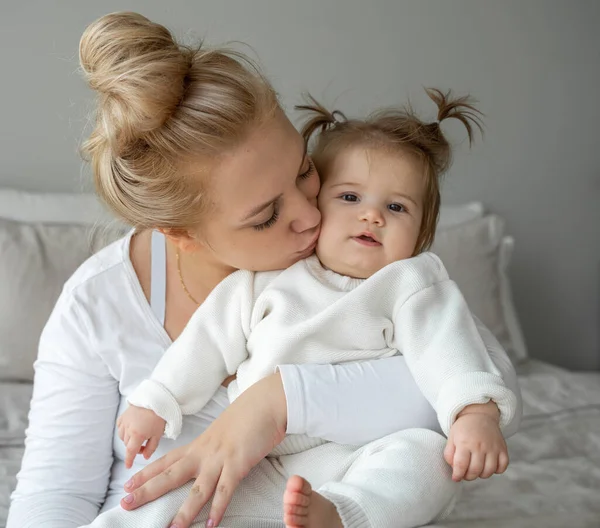 Portrait of young tired Mother and baby girl looking at camera in bedroom home. Child care, domestic life routine, healthy lifestyle. Exhausted woman take care about child and household duties. Copy space