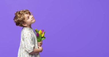 Mor arka planda duran, sarı lale buketini tutan beyaz, sevimli anaokulu kızı sola bakıyor. Reklam için kopyalama alanı. Bahar tazeliği alışverişi konsepti