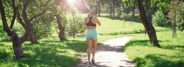 Middle-aged slim caucasian woman sportswear running, jogging training in park in sunny day summer. Leisure activity, healthy lifestyle. Banner copy space