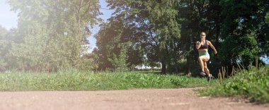 Middle-aged slim caucasian woman sportswear running, jogging training in park in sunny day summer. Leisure activity, healthy lifestyle. Banner copy space