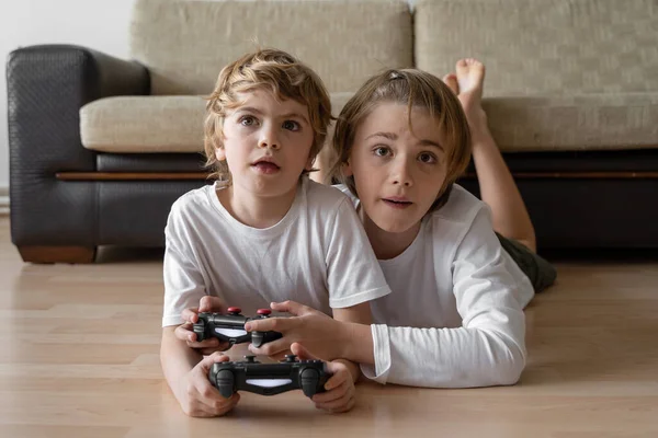Addicted children playing video game playstation joystick controller at home. Harm of online gadget entertainment technology to human health.