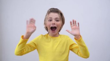 Impressed Emotional Teenager happily Joy Gift News Over White Background. Blond Kid With Long Hair And Yellow T-Shirt Waving Hands Excited