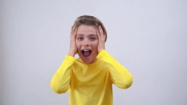 Impressed Emotional Teenager happily Joy Gift News Over White Background. Blond Kid With Long Hair And Yellow T-Shirt Waving Hands Excited