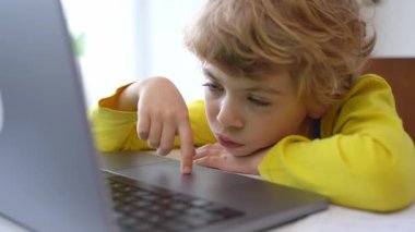 Bored Schoolboy child using laptop online educational lesson course at home. Distance learning course remote video conference. Schoolgirl study does school homework.