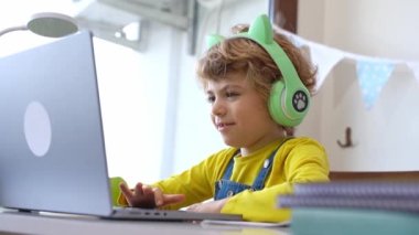 Kulaklıklı şirin, zeki, beyaz, ilkokul çocuğu bilgisayar eğitimi alıyor. Dijital derste öğretmenlik, evde bilgisayar dersinde internet dersi. Sanal eğitim kursu. Öğrenci kız ders çalışıyor.