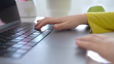 Close up Schoolboy child hands typing keyboard using touchscreen laptop online educational lesson course at home. Distance learning course remote video conference. Schoolgirl study does school