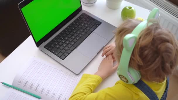 家庭でノートパソコンとヘッドフォンをオンライン教育レッスンコースを使用して小学生 遠隔ビデオ会議を学ぶ距離 女子高生は宿題をする 親戚の友人と子供の呼び出し — ストック動画