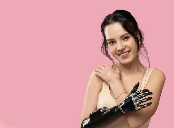 Slim Disabled Woman with Prosthetic Arm, Artificial Hand Smiling To Camera Over Pink Background. Women Beauty Diversity. Positive. Copy space