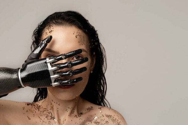 Тонкая женщина-инвалид с протезной рукой, искусственная рука с блестящим свежим макияжем, смотрящая на камеру на бежевом фоне. Красота разнообразие женщин. Абсолютно. Копировальное пространство