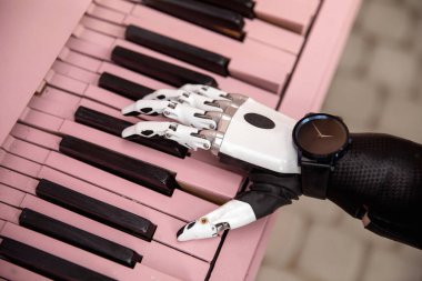 Bionic artificial hand prosthetic arm playing pink piano. Negative space. Concept of diversity and possibilities.