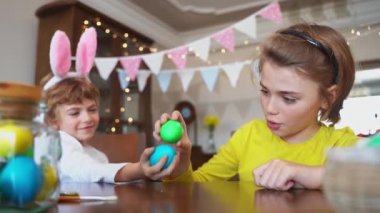Easter Sunday Family holiday traditions. Two caucasian happy siblings kids with bunny ears fighting with multi-colored Easter painted eggs. Having fun together