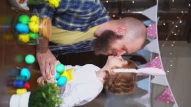 Paskalya Ailesi gelenekleri. Paskalya bayramında baba ve anaokulu çocuğu tavşan kulaklı Paskalya yumurtalarıyla oynayıp resim yapıyorlar. Sıcak sarılma Dikey