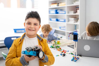 Robot lego programlama sınıfı. Çocuklar robot lego yapıp kodluyorlar. İnşaat blokları, dizüstü bilgisayar ve uzaktan kumandalı joystick kullanarak STEM eğitimi. Okul çocukları için teknolojik eğitim gelişimi
