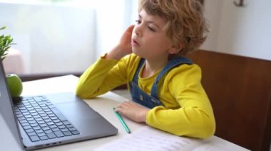 Bored Schoolboy child using laptop online educational lesson course at home. Distance learning course remote video conference. Schoolgirl study does school homework.