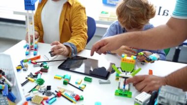 Robot programlama dersi. Çocuklar robot yapıp kodluyorlar. İnşaat blokları, dizüstü bilgisayar tableti, uzaktan kumandalı joystick kullanarak STEM eğitimi. Okul çocukları için teknolojik eğitim gelişimi