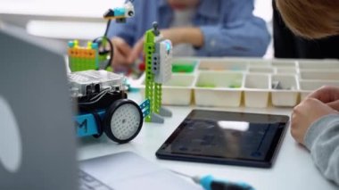 Robot programlama dersi. Çocuklar robot yapıp kodluyorlar. İnşaat blokları, dizüstü bilgisayar tableti, uzaktan kumandalı joystick kullanarak STEM eğitimi. Okul çocukları için teknolojik eğitim gelişimi
