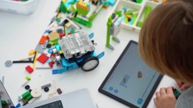 Robot programlama dersi. Çocuklar robot yapıp kodluyorlar. İnşaat blokları, dizüstü bilgisayar tableti, uzaktan kumandalı joystick kullanarak STEM eğitimi. Okul çocukları için teknolojik eğitim gelişimi