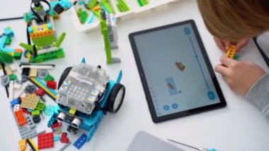Robot programlama dersi. Çocuklar robot yapıp kodluyorlar. İnşaat blokları, dizüstü bilgisayar tableti, uzaktan kumandalı joystick kullanarak STEM eğitimi. Okul çocukları için teknolojik eğitim gelişimi