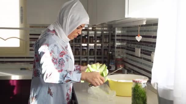 キッチンでカリフラワーを調理する中年のイスラム教徒の女性 ヒジャーブスカーフを身に着けている食品 自宅でイスラム教徒の女性 家庭生活習慣 — ストック動画