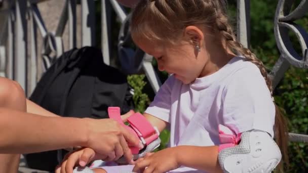 Anya Felveszi Görkorcsolyás Könyökvédőt Lánya Gyerekének Nyilvános Parkban Nyáron Családi — Stock videók